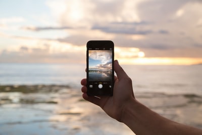 手持智能手机展示海洋的人